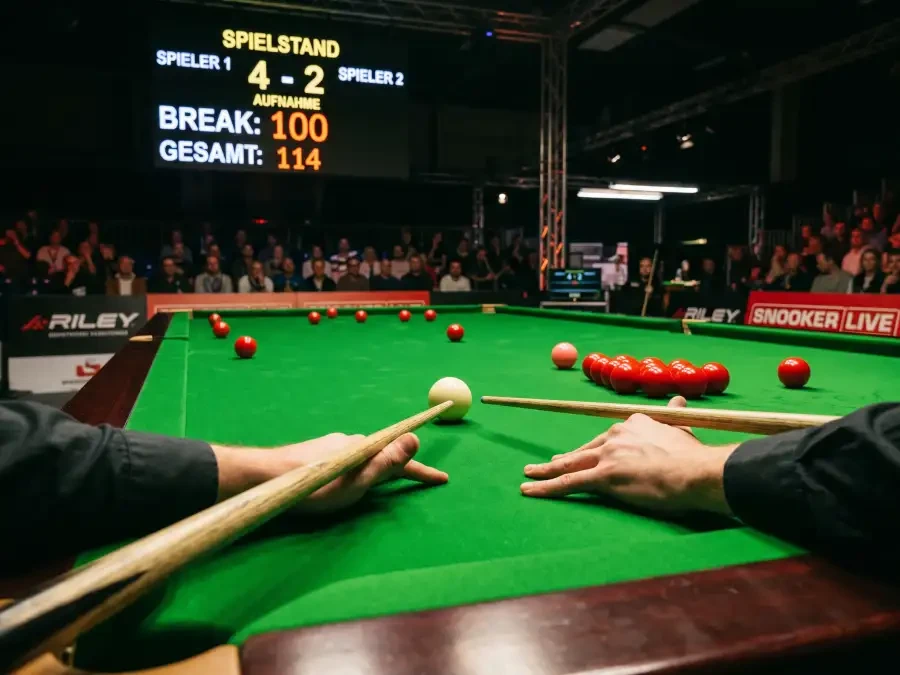 Snooker-Spieler am Tisch während eines Century Breaks mit Scoreboard im Hintergrund