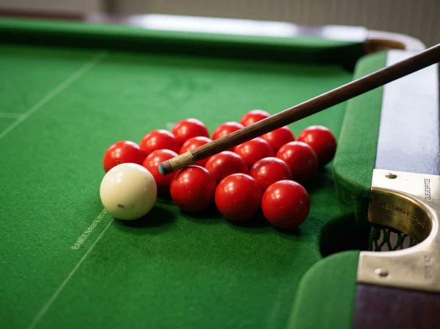 Nahaufnahme von Snooker-Kugeln auf grünem Tuch mit Queue